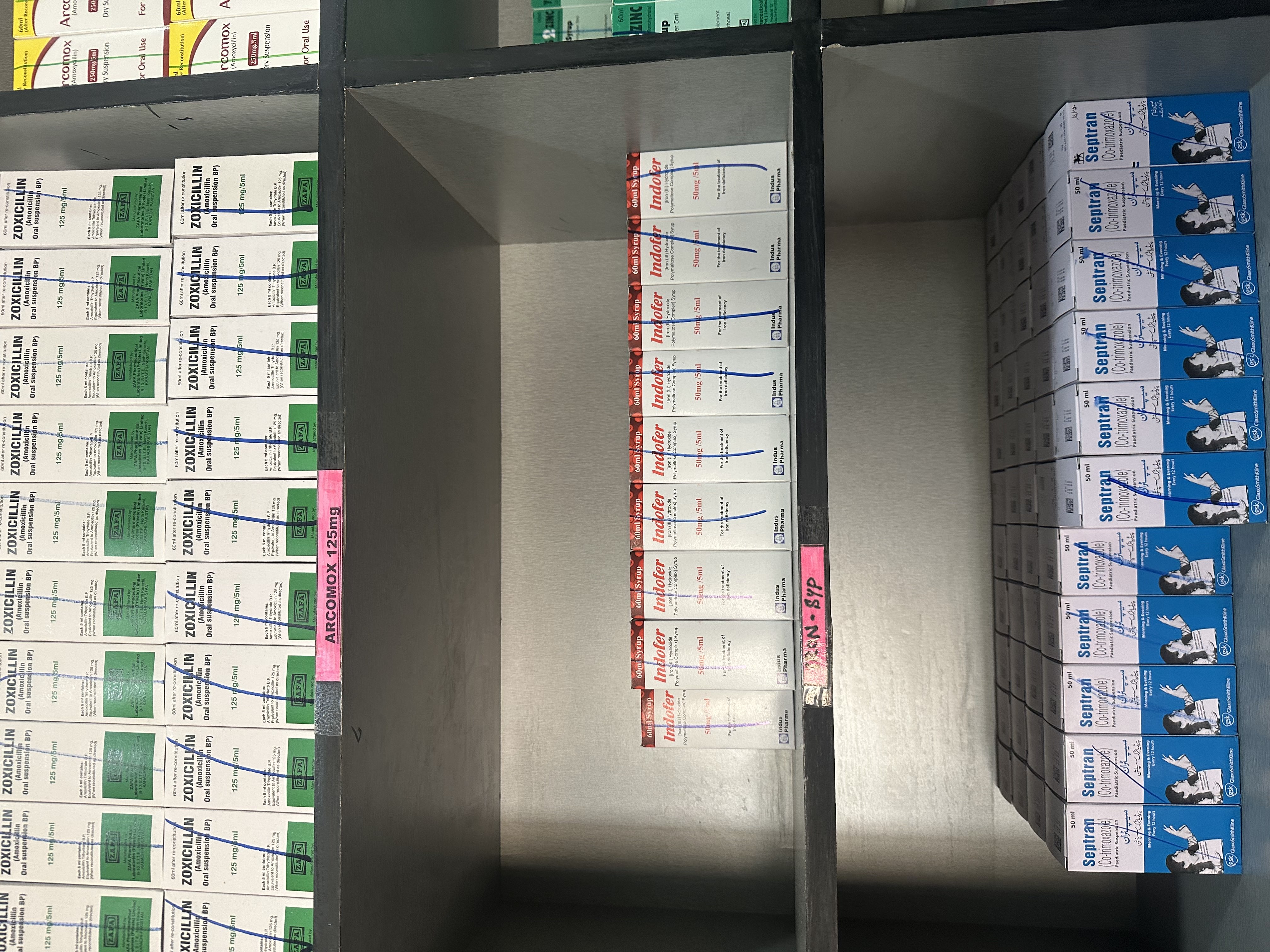 Pharmacy shelves stocked with iron syrup and paediatric suspensions.
